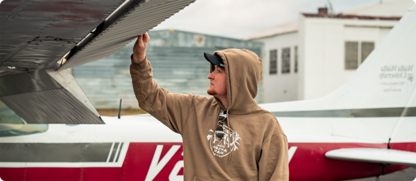 A student inspects the underside of an airplane wing.